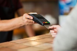 modern technology and people concept - man or bartender with payment terminal and customer hand with credit card at bar of coffee shop